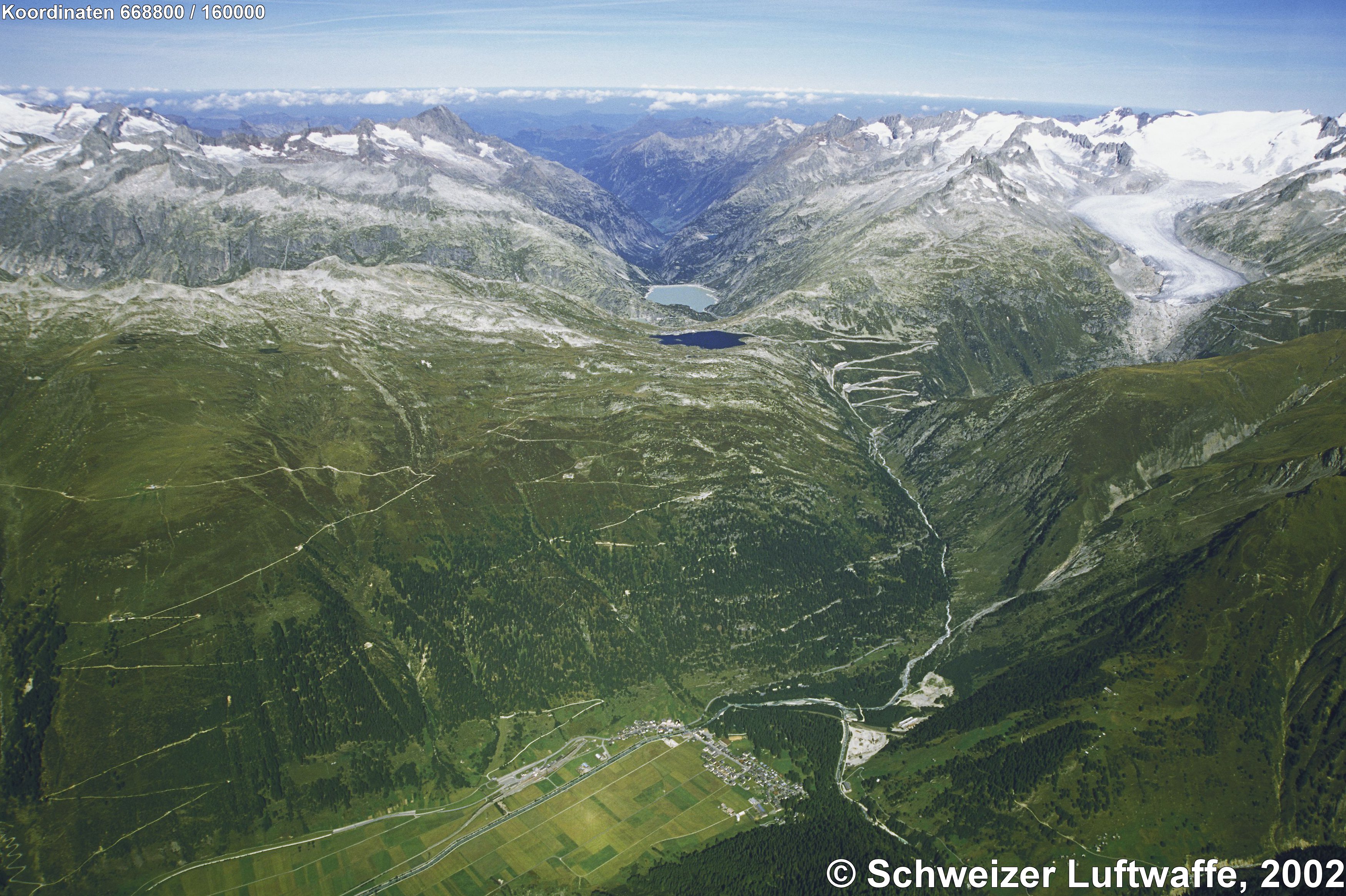 Blick von Oberwald im Goms (VS) zum Grimselpass. 'Totesee' und 'Räterichsbodensee' in der Bildmitte. Rechts Rhonegletscher und Furkapassstrasse.